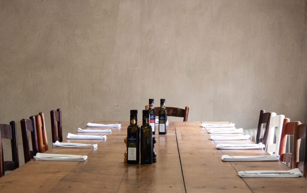 Long timber table set with cutlery and napkins and served with glass bottles of oil and condiments before serving dinner